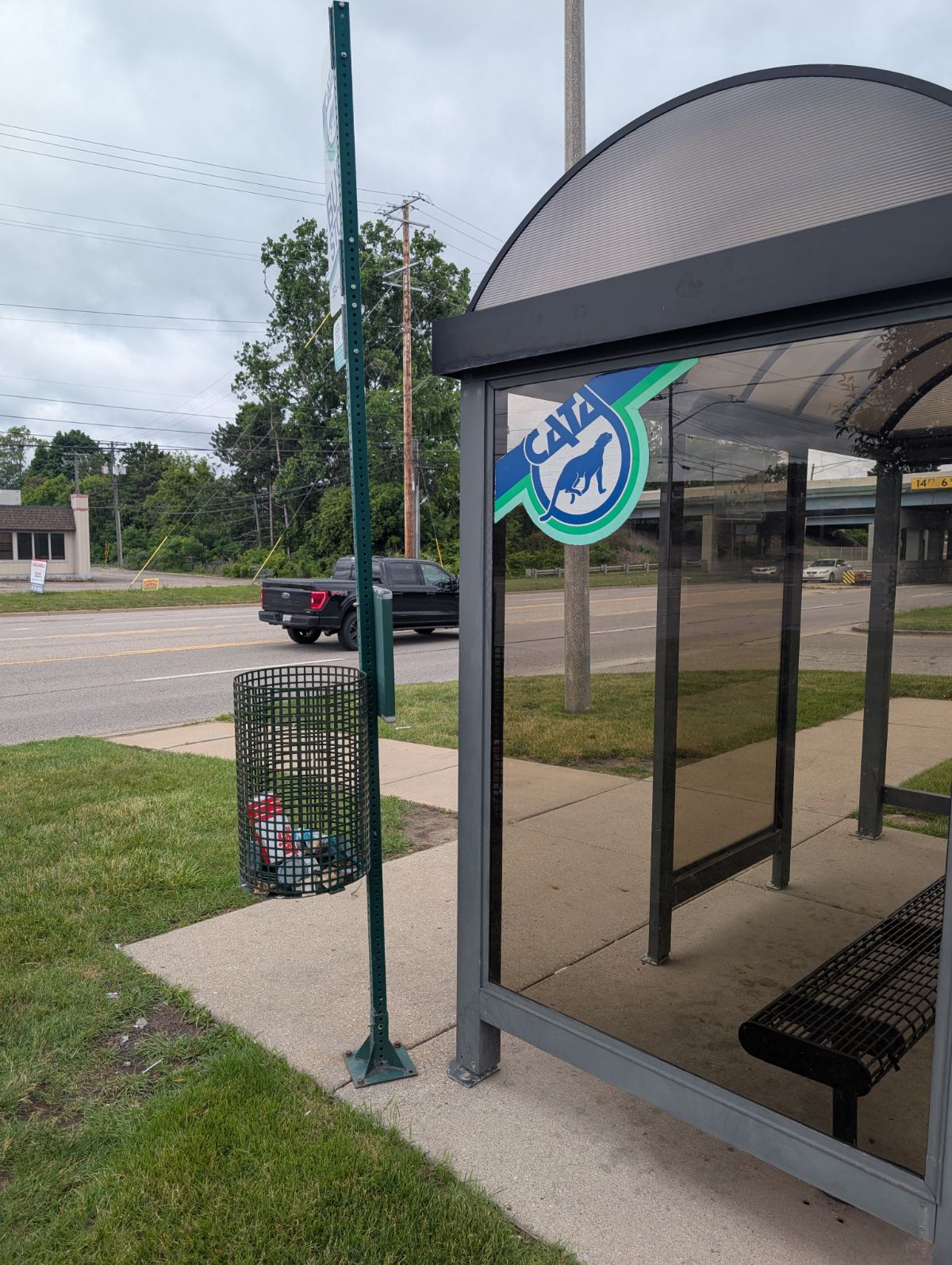 A CATA bus shelter on a wide road in Lansing, surrounded by pavement