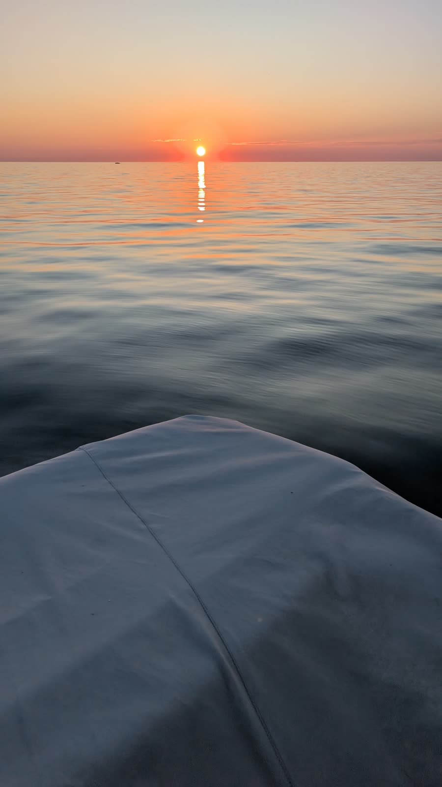 Sun sitting on the horizon over Lake Michigan, silky water, shot from a boat