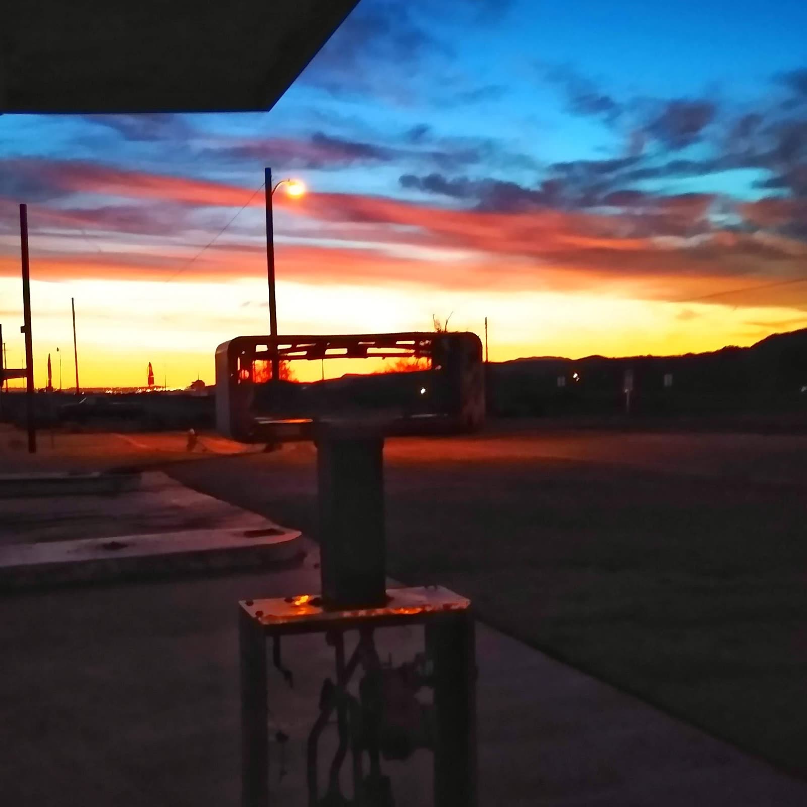 A vivid sunset over an empty lot, a streetlight catching the last light